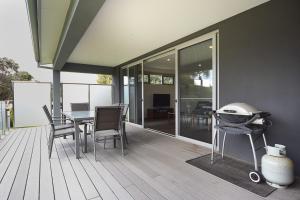 a deck with a grill and a table and chairs at Rolling Waves in Pt Leo in Shoreham