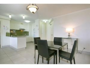 a dining room with a glass table and green chairs at Coolum Caprice in Coolum Beach