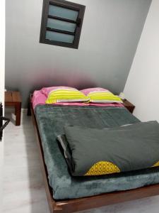 a bed with pink and yellow pillows in a room at studio meublé près de la mare à joncs in Cilaos