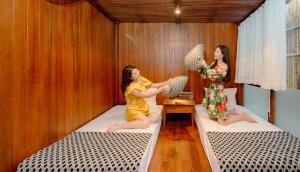 two girls are sitting on beds in a room at Villa FLC Hạ Long bt3-6 in Ha Long