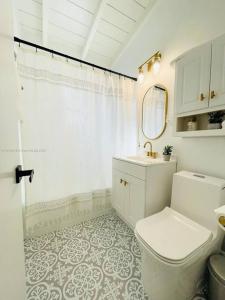a bathroom with a toilet and a sink and a mirror at Tropical Oasis House Private Pool Family Yard in Fort Lauderdale