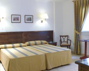 a bedroom with a large bed and a chair at Hotel Tio Felipe in Carboneras