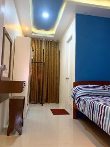 1 dormitorio con cama y pared azul en The Ideal Place in Cauayan city en Ciudad de Cauayán