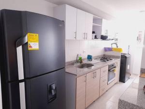uma cozinha com um frigorífico preto num quarto em Hermoso apartamento con piscina ubicado cerca a los principales centros comerciales em Ibagué