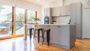 Una cocina con gabinetes blancos y taburetes de bar. en Mendi-Moke, en Flinders