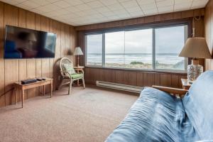 a bedroom with a bed and a large window at The Hamptons in Rockaway Beach