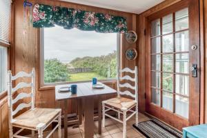 a dining room with a table and chairs and a large window at The Hamptons in Rockaway Beach