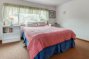 a bedroom with a bed with a checkered blanket and a window at The Hamptons in Rockaway Beach
