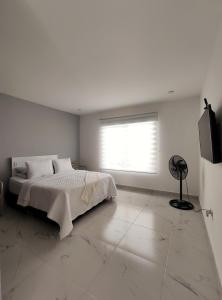 a white bedroom with a bed and a window at Cabañas Compostela Gigante in Gigante