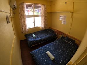 Zamamia International Guesthouse في Shimajiri: سريرين في غرفة صغيرة مع نافذة