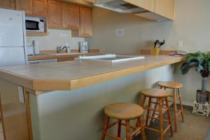 林肯市的住宿－Waters Edge 308，厨房配有带凳子的柜台和冰箱。