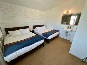 a small room with two beds and a sink at Sierra Motor Lodge - A Sierra Blue Hotel in Mojave