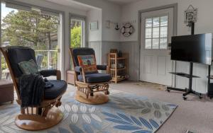 a living room with two chairs and a flat screen tv at Breeze Cottage in Depoe Bay