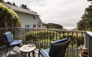 Un balcón con sillas, una mesa y el océano en Breeze Cottage, en Depoe Bay