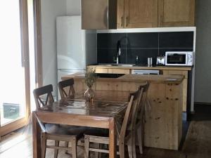 une cuisine avec une table en bois avec des chaises et un comptoir dans l'établissement Appartement 2 Pièces + Coin Montagne pour 6 avec Parking et Wi-Fi - FR-1-762-20, à Saint-Chaffrey