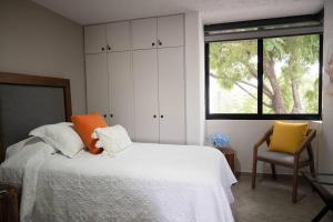 グアダラハラにあるNUEVO depto - Glorieta Chapalitaのベッドルーム1室(ベッド1台、椅子、窓付)