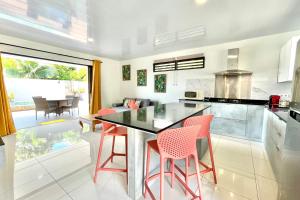 une cuisine avec des chaises rouges et un comptoir noir dans l'établissement Muna house and private pool - AC - optic fiber Wi-Fi - 3 pers, à Punaauia