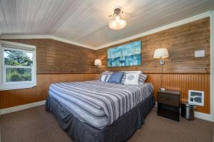 1 dormitorio con 1 cama en una habitación con paredes de madera en Cunningham Coop, en Seaside