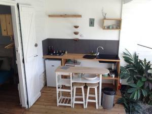 una pequeña cocina con mesa de madera y taburetes en LE ZAYENN gîte côté canne, en Grand-Bourg