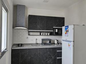 uma cozinha com um frigorífico branco e uma bancada preta em Rio Parana alta Vista em Corrientes