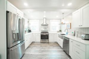 a kitchen with white cabinets and a stainless steel refrigerator at The Duffy House in Seaside