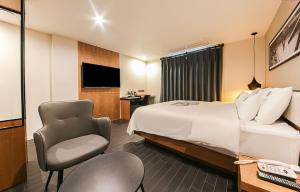 Habitación de hotel con cama y silla en Gray 191 Hotel en Busan