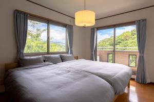 sypialnia z dużym białym łóżkiem i dużymi oknami w obiekcie ANGO ATAMI I w mieście Atami