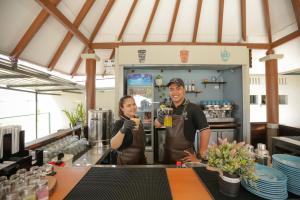 two people standing in a kitchen holding drinks at Damar Toba in Balige