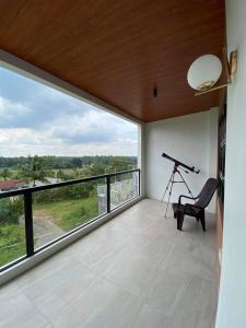 Zimmer mit einem Teleskop und einem Stuhl auf dem Balkon in der Unterkunft The Sunset House in Lucban