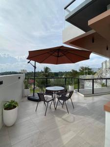eine Terrasse mit einem Tisch, Stühlen und einem Sonnenschirm in der Unterkunft The Sunset House in Lucban