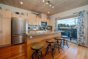 a kitchen with a stainless steel refrigerator and bar with stools at Tranquility Cove in Depoe Bay