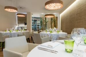 a restaurant with white tables and white chairs and chandeliers at Laguna Park Hotel 4Superior in Bibione