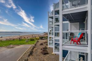a house on the beach with a red chair on the balcony at Waters Edge 207 in Lincoln City