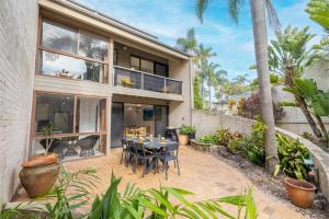 a patio with a table and chairs in front of a house at The Moorings 18 4 Cromarty Rd Waterfront, Pool, Wifi & AirCon in Soldiers Point