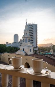 two cups of coffee sitting on a table with a clock tower at Amara Living in Cartagena de Indias