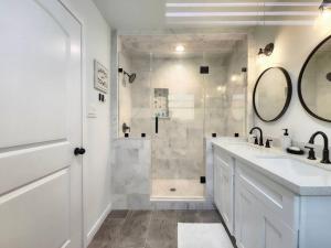 a bathroom with a shower and two sinks and a mirror at NEW! H-Town Getaway Near Medical Center! in Houston
