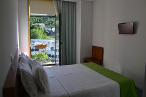 um quarto com uma cama e uma janela com vista em Hotel Comércio em Resende