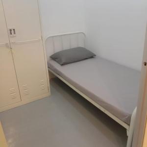 een kleine slaapkamer met een wit bed en een kast bij D'Bernam Homestay in TanjongMalim