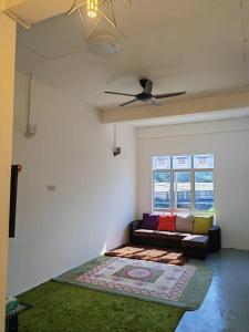 uma sala de estar com um sofá e uma ventoinha de tecto em D'Bernam Homestay em TanjongMalim