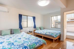a bedroom with two beds and two windows at 新宿6丁目戸建 in Tokyo