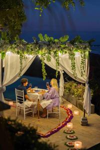 two people sitting at a table under a gazebo at The Acala Shri Sedana in Nusa Lembongan