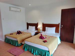 two beds in a hotel room with flowers on them at D.R. Lanta Bay Resort in Ko Lanta