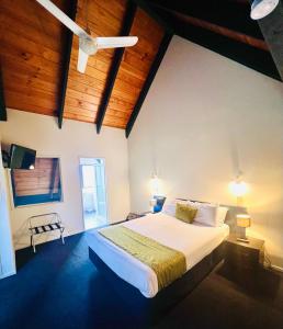 1 dormitorio con 1 cama blanca grande y techos de madera en Wylie Court Motor Lodge en Rotorua