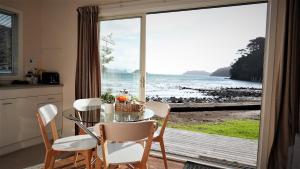 大堡礁岛Karaka Bay Lodge的一间带桌子并可欣赏海景的餐厅