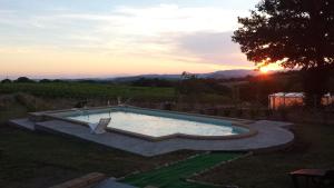 uma piscina num quintal com um pôr-do-sol ao fundo em Agriturismo Airone em Pitigliano