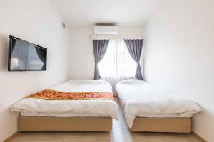 Duas camas num pequeno quarto com uma janela em Uji Cha-gan-ju-tei House em Uji