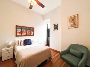 a bedroom with a bed and a green chair at Amazing experience in Casco Viejo historical site1 in Panama City