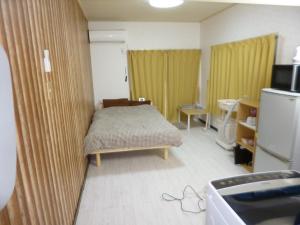 een kleine kamer met een bed en een koelkast bij Stay Like Living IJIRI 103 in Shiobaru