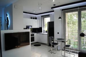 uma cozinha com uma mesa e uma televisão de ecrã grande em Apartament Exclusive em Poznań