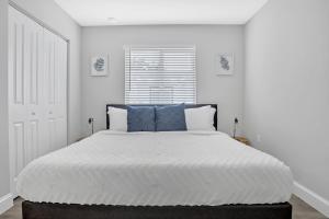 a white bedroom with a large bed with blue pillows at Sistrunk Shades Villas #3 - Brand New Townhomes Downtown Fort Lauderdale in Fort Lauderdale